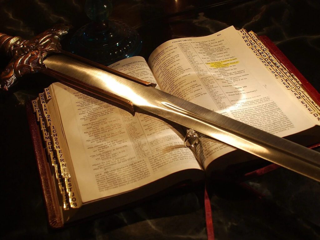 Una Biblia abierta con una espada de metal en sus páginas, ilustrando el poder de la Palabra de Dios para discernir pensamientos e intenciones.