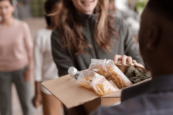 Una persona que entrega comida a alguien necesitado, lo que representa la práctica bíblica de cuidar a los pobres.