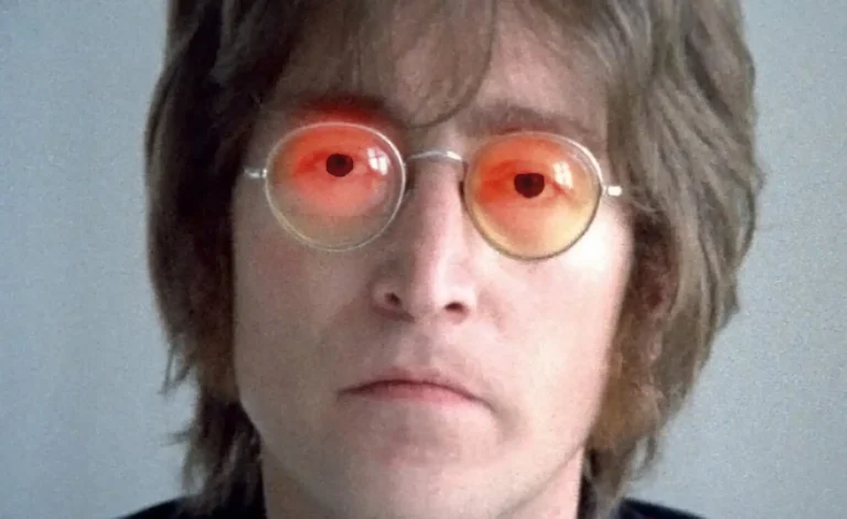 John Lennon con gafas redondas y un reflejo rojo en los ojos, simbolizando la ideología detrás de 'Imagine' en un análisis cristiano.