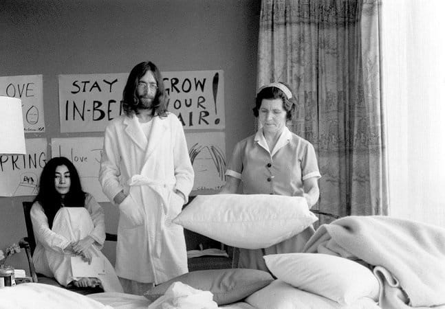 John Lennon e Yoko Ono na cama, enquanto uma empregada arruma o quarto. Imagem icônica da hipocrisia por trás da utopia de 'Imagine'